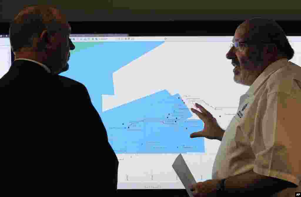 Mike Barton, rescue coordination chief, right, shows Australia's Deputy Prime Minister, Warren Truss, the map of the Indian Ocean search areas during a tour of the Australian Maritime Safety Authority's rescue coordination center in Canberra, March 23, 2014.