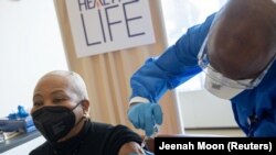 Une femme reçoit une dose du vaccin Pfizer-BioNTech contre la maladie COVID-19 à l'hôpital de Harlem à New York, aux États-Unis, le 25 février 2021.
