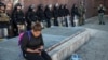 A woman checks her phone while police officers monitor the situation near a CVS pharmacy that was looted and burned by rioters on Monday after the funeral of Freddie Gray, on April 29, 2015 in Baltimore, Maryland. 