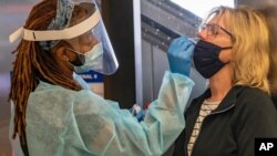 Traveler Patty Siegel of Los Angeles gets a COVID-19 nasal swab test before a planned trip to Hawaii at the Los Angeles International Airport in Los Angeles, Nov. 25, 2020. 