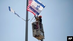 A worker hangs Israeli and American flags on a lamppost along a freeway leading to Jerusalem, days before a planned visit by President Donald Trump, May 16, 2017.
