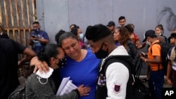 Lizeth Morales de Honduras y su hijo Alex Cortillo, reciben un abrazo de Erika Valladares Ponce, mientras esperan cruzar a Estados Unidos para comenzar el proceso de asilo el lunes 5 de julio de 2021 en Tijuana, México.