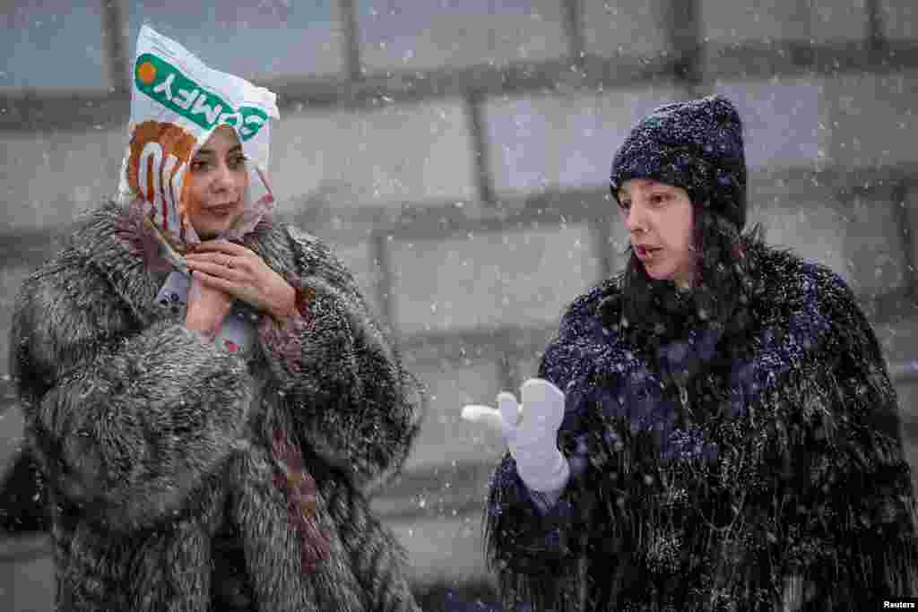 Women walk on a snow-covered street during a snowfall, in Kyiv, Ukraine. REUTERS/Alina Smutko