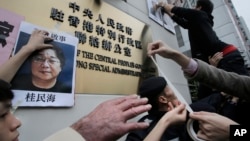 香港抗議者在北京駐香港機構中聯辦前貼上銅鑼灣書店失踪老闆桂民海的照片。 （2016年1月3日）