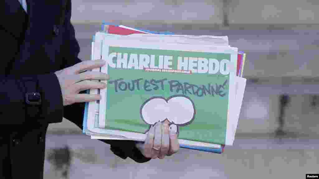 Le Premier ministre français Manuel Valls, avec un exemplaire de Charlie Hebdo en mian, quitte la réunion hebdomadaire du cabinet à l'Elysée à Paris, France, le 14 janvier 2015.