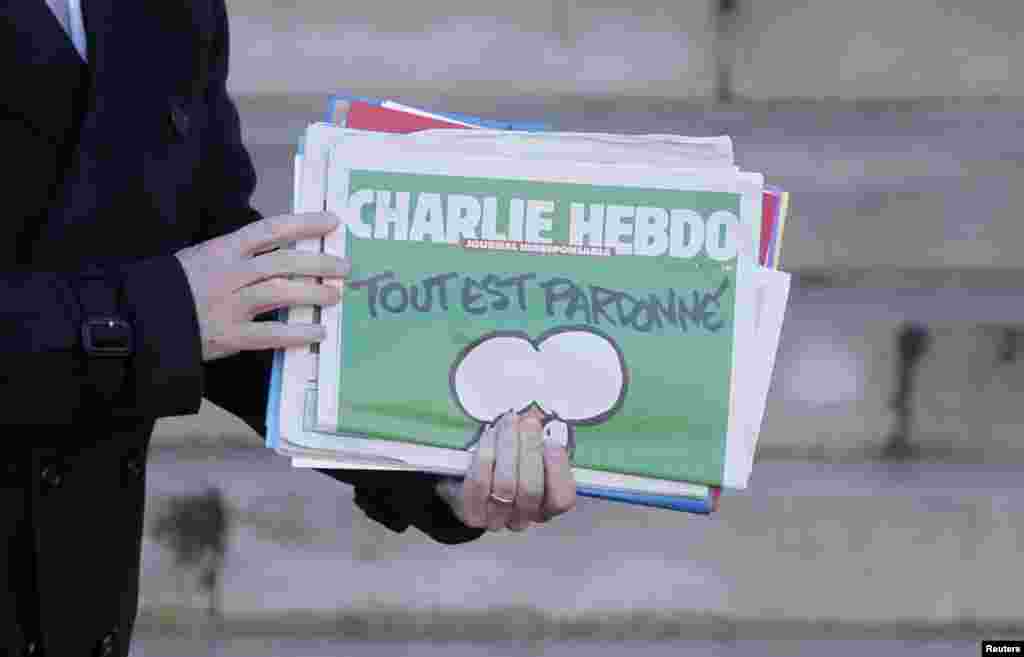 Perdana Menteri Perancis Manuel Valls memegang tabloid Charlie Hebdo saat ia meninggalkan rapat kabinet di Istana Elysee di Paris, Perancis (14/1). (Reuters/Christian Hartmann)