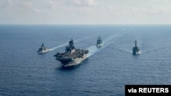 Kapal pengawal milik angatan laut Australia yang dilengkapi dengan peluru kendali HMAS Parramatta (FFH 154) (kiri) berlayar bersama kapal perang milik angkatan laut AS dalam sebuah patroli di laut China Selatan pada 18 April 2020. (Foto: U.S. Navy via Reuters)