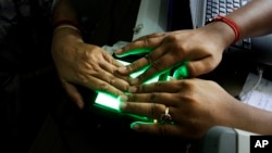 FILE- An operator helps an elderly woman scan her fingerprints as she enrolls for Aadhar, India's unique identification project in Kolkata, India, May 16, 2012. India's top court has ruled that the right to privacy is a fundamental right of every citizen 