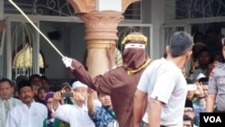 Dalam foto dokumentasi ini, algojo pelaksana cambuk mengayunkan rotan ke punggung pelanggar syariah di Banda Aceh, 19/9/2014 (Foto: VOA/Budi Nahaba)