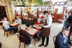 An employee, wearing a protective face mask, serves customers during the reopening of the hall of the Mesturet restaurant amid the coronavirus disease (COVID-19) in Paris, June 15, 2020.
