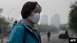 A woman wears a protective mask to fight bad air pollution in Beijing on October 22, 2018. (Photo by Nicolas ASFOURI / AFP)