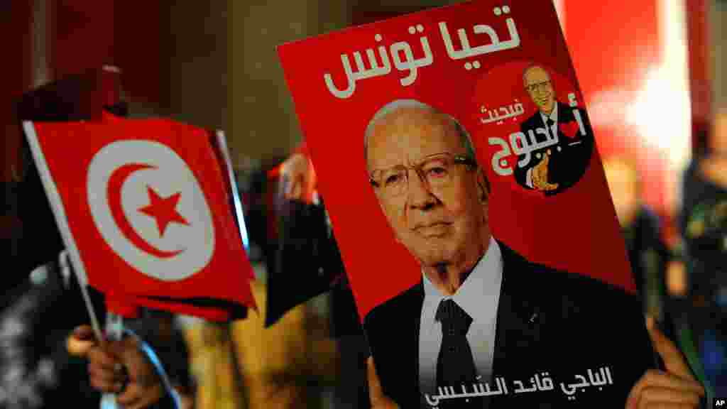 Un partisan tenant une affiche du candidat présidentiel tunisien Béji Caïd Essebsi, célèbre après les premiers résultats du second tour de l'élection présidentielle en Tunisie, à Tunis, dimanche 21 décembre 2014.