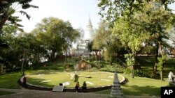 ស្រ្តី​ពីរ បី​នាក់ អង្គុយ​នៅ​លើ​គែម​នាឡិកា​ដ៏​ធំ​នៅ​ក្នុង​បរិវេណ​រមណីយដ្ឋាន​វត្តភ្នំ ដែល​ស្ថិត​នៅក្នុង​រាជធានី​ភ្នំពេញ នៃ​ប្រទេស​កម្ពុជា។