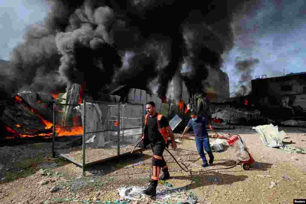 Un bombero palestino camina mientras participa en los esfuerzos para apagar un incendio en una fábrica de esponjas después de que fue alcanzada por proyectiles de artillería israelí, según testigos.
