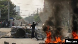 Seorang demonstran berdiri dekat barikade dalam unjuk rasa memprotes kudeta militer di Mandalay, Myanmar, 22 March 2021. 