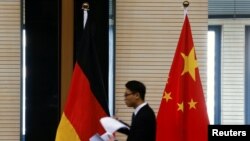 在北京舉行中德經貿部長會議期間一名男子走過中國和德國國旗。 （資料照片）