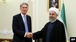 Iran's President Hassan Rouhani (R) welcomes British Foreign Secretary Philip Hammond at the start of their meeting in his office, in Tehran, Iran, Aug. 24, 2015.