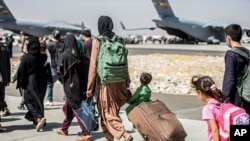 FILE - Families walk towards their flight during evacuations at Hamid Karzai International Airport, in Kabul, Afghanistan, Aug. 24, 2021, in this photo provided by the U.S. Marine Corps. (Sgt. Samuel Ruiz/U.S. Marine Corps via AP)