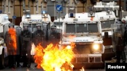 Api berkobar di depan polisi di Jalan Springfield saat protes berlanjut di Belfast, Irlandia Utara, 8 April 2021. (Foto: Reuters)