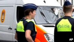 FILE - Police officers stand near a bomb squad van in central Antwerp, Belgium, June 18, 2016. Belgian police raided 15 homes in the cities of Antwerp, Ghent and Deinze, taking 15 people in for questioning.