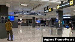 FILE - Travelers walk in a quiet arrivals terminal at Washington Dulles International Airport in Dulles, Virginia, Nov. 19, 2020. 