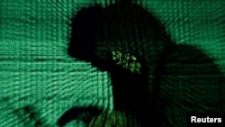 FILE - A man holds a laptop computer as cyber code is projected on him in this photo illustration.
