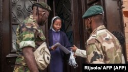 Des soldats de l'armée malgache distribuent des masques et des échantillons d'une tisane présentée par le président Rajoelina comme un remède contre le coronavirus à la population à Antananarivo à Madagascar, le 22 avril 2020.