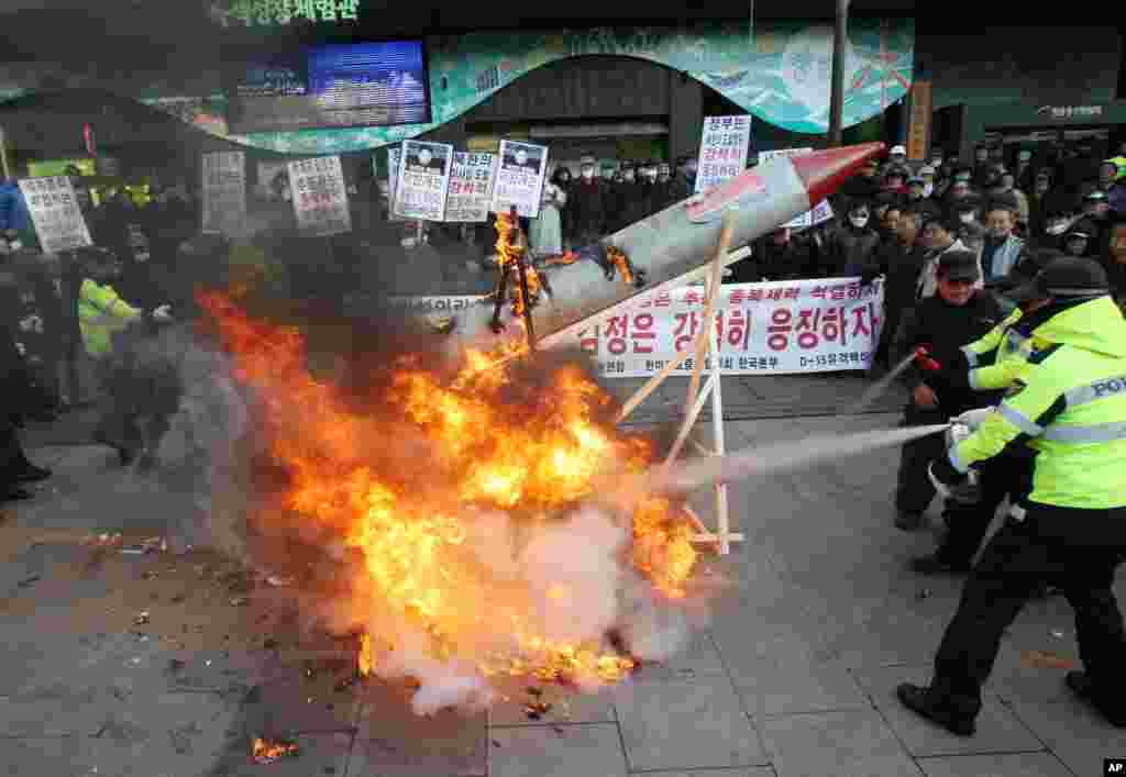 12일 한국 서울에서 북한 로켓 발사 규탄하며 모형 로켓을 불 태운 시위대. 경찰이 소화기를 동원해 불을 끄고 있다.