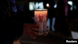 Una católica boliviana sostiene velas con la efigie del papa Francisco en el exterior del Hospital Gemelli de Roma, donde el pontífice está hospitalizado por una infeccción respiratoria, el 18 de febrero de 2025.