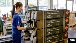 Співробітниця німецької збройової компанії Rheinmetall готує 120-мм боєприпаси для танків Leopard, які будуть доставлені українським Збройним Силам, на заводі Rheinmetall в Унтерлюсс, північна Німеччина, 6 червня 2023. Фото Акселя Хеймкена / AFP