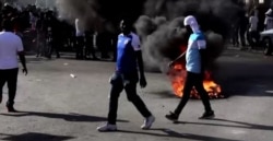 Un neumáticos en llamas el domingo 28 de febrero de 2021 en nuevas portestas en Haití. [Captura de pantalla/Video de Reuters]