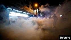 Seorang pria terlihat, setelah polisi anti huru hara menembakkan gas air mata ketika ia duduk di Yuen Long. (Foto: Reuters)…