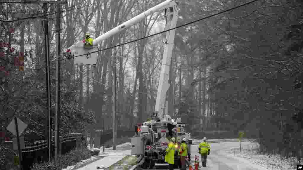 Les employés de Duke Energy, une campagne électrique, travaillent pour rétablir le courant dans un quartier à Matthews, Caroline du Nord, 22 janvier 2016. Une tempête de neige massive a commencé à tomber sur le sud et l'est des États-Unis avec des annulations de vols de masse, cinq Etats déclarant l'état d'urgence et plus de 2 pieds (60 centimètres) prédit pour Washington seul. 