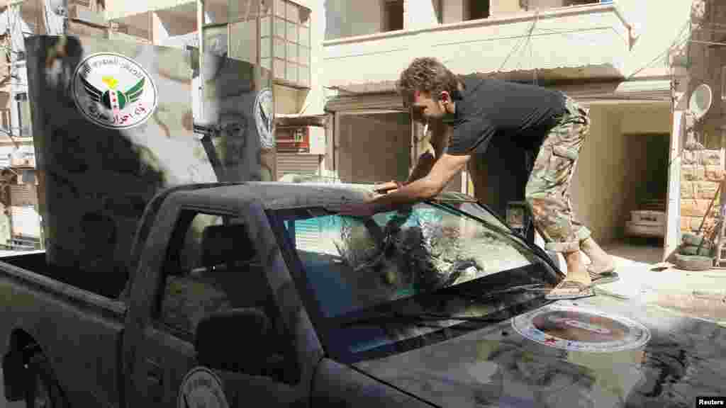 A member of "Free Men of Syria" brigade, operating under the Free Syrian Army, washes a vehicle in Aleppo's Bustan al-Qasr, Sept. 9, 2013.