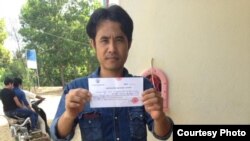 Chhoun Chheng shows his registration slip after authority in Pailin province allowed him to register there. Chheng was refused twice before at two other provinces.