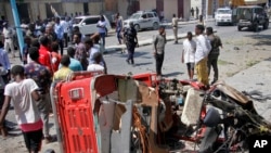 Warga Somalia berkumpul di dekat rongsokan kendaraan berisi bom yang meledak di luar sebuah restoran di Mogadishu, hari Kamis (28/3).
