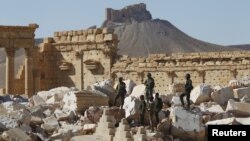 Pasukan Suriah berdiri di antara reruntuhan bangunan di kota kuno Palmyra di provinsi Homs, Jumat (1/4).
