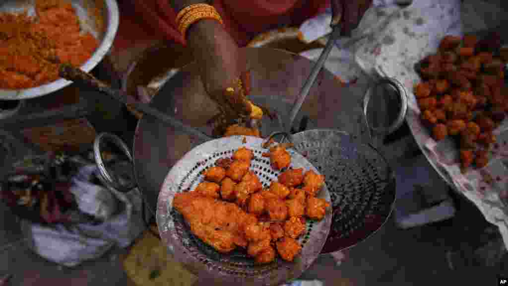 Une femme vend des baignets qu'elle prépare avec ses mains. Des maladies contagieuses peuvent être évitées avec le lavage regulier des mains. (AP Photo/Saurabh Das)