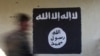  FILE - A soldier walks past a black flag commonly used by Islamic State militants. 