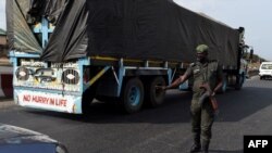 A police officer, wearing a face mask customised for the anti-robbery Rapid Respond Squad (RRS) as preventive measure against the COVID-19 coronavirus, flags down a car at a check point in Lagos, on April 20, 2020. 