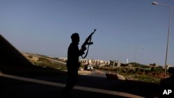 Un rebelle libyen sécurise un poste de contrôle à Benghazi, Libye, le 30 mars 2011.
