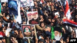 Ribuan warga Irak berkumpul di alun-alun di pusat kota Baghdad untuk memperingati setahun pembunuhan Jenderal Iran Soleimani dan pemimpin milisi Irak Abu Mahdi al-Muhandis, hari Minggu (3/1). 