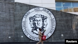 Un hombre camina frente al emblema de The City College of New York en Manhattan. 