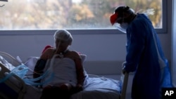 Un trabajador de la salud atiende a un paciente en una unidad de cuidados intensivos designada para personas infectadas con COVID-19 en un hospital en Buenos Aires, Argentina, el viernes 2 de octubre de 2020.