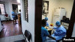 Trabajadores médicos toman muestras de sangre de un hombre para una prueba rápida de la enfermedad por coronavirus (COVID-19) en un centro médico debido al brote de COVID-19 en Caracas, Venezuela, 15 de abril de 2020.