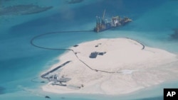 In this Feb. 25, 2014 file photo taken by surveillance planes and released May 15 by the Philippine Department of Foreign Affairs, a Chinese vessel, top center, is used to expand structures and land on the Johnson Reef, called Mabini by the Philippines and Chigua by China, at the Spratly Islands in the South China Sea, Philippines. The Philippines wants an international tribunal to issue a decision as quickly as it can on a Manila complaint that questions the legality of China's massive territorial claims in the South China Sea because the disputes continue to escalate. Foreign Secretary Albert del Rosario said late Tuesday, June 17 that the Philippines would ask its lawyers to petition the Arbitral Tribunal in the Hague, the Netherlands, to issue an earlier ruling after China said it would not get involved in the case, which should shorten the arbitration proceedings. (AP Photo/Philippine Department of Foreign Affairs, File)