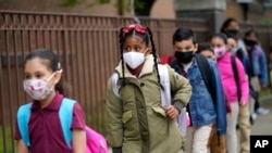Para siswa berbaris sebelum memasuki Sekolah Dasar Christa McAuliffe di Jersey City, New Jersey, pada 29 April 2021. (Foto: AP/Seth Wenig)