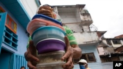 Un voluntario lleva recipientes con arroz, pollo y ensalada para los residentes del comedor de beneficencia San Antonio de Padua en el barrio Petare de Caracas, el 10 de junio de 2021.