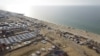 Foto udara menunjukkan warga Palestina berkumpul di pantai menunggu bantuan kemanusiaan yang dijatuhkan dari udara di Gaza, di tengah konflik Israel dan Hamas, di kota Deir Al-Balah, Jalur Gaza tengah. 