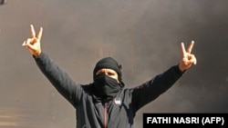Un Tunisien brandit le V comme signe de victoire alors que des jeunes brûlent des pneus et bloquent des routes dans la ville de Tataouine, au sud du pays, le 12 février 2021.